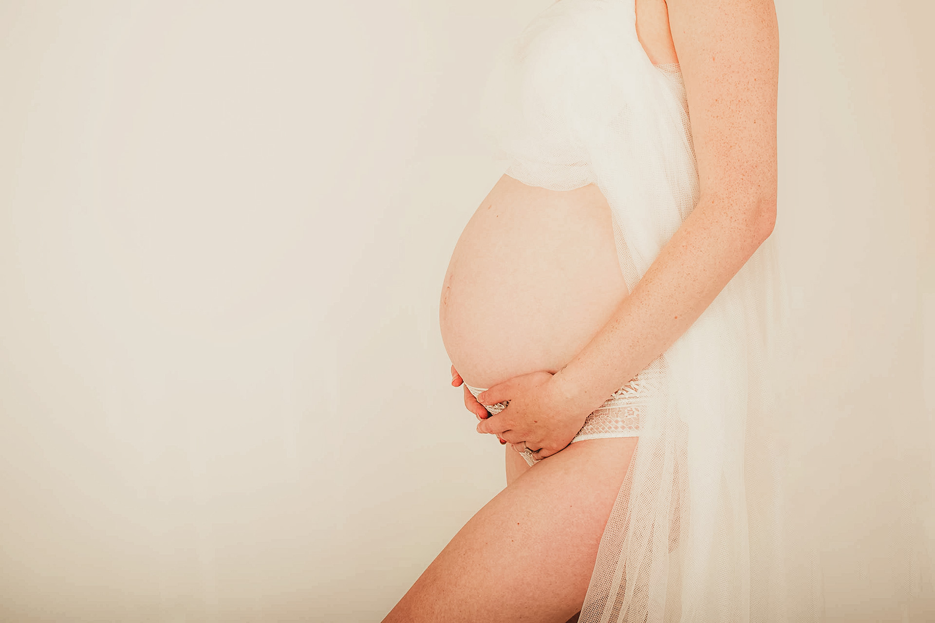 Photo of a baby bump with a white backdrop, studio shooting.